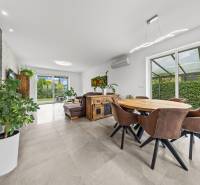 Interior of a family house with a dining area, leather chairs, and a view of the garden.