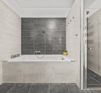 Gray bathroom with a bathtub and a shower in a family house.