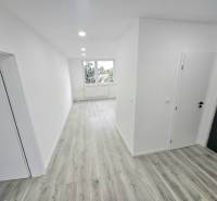 A hallway in a 3-room apartment with wooden flooring and white walls.