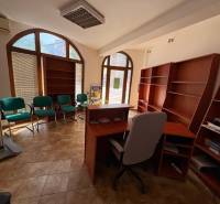 Commercial premises with an office chair, green armchairs, and wooden shelves.