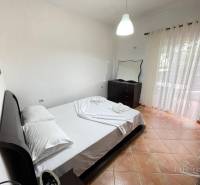 Bedroom in a holiday apartment with a double bed, dresser, and balcony.