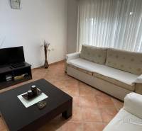 Living room in a holiday apartment with sofas, a table, and a television.