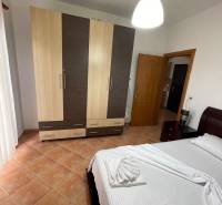 Bright bedroom in a holiday apartment with a bed, wardrobe, and tiled floor.
