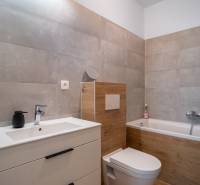 A bathroom in a family house with a bathtub, sink, and toilet in neutral tones.