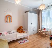 Children's room in a family house with a bed, wardrobe, and toys on a wooden floor.