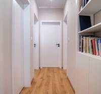 A hallway in a family house with a wooden floor and a bookshelf full of books.