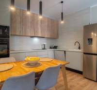 A kitchen in a family house with a wooden table, a refrigerator, and a built-in oven.