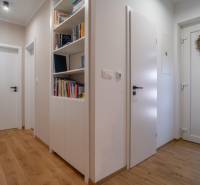 The hallway of a family house with bookshelves, wooden flooring, and decorated doors.