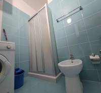 A bathroom in a holiday apartment with a washing machine, shower, and bidet.