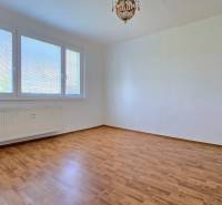A bright room with a large window, wooden floor, and radiator in a 3-room apartment.