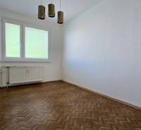 A room in a 3-room apartment with wooden flooring, white walls, and a window with blinds.