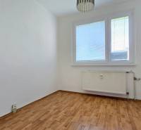 An empty room with a wooden floor and a radiator in a three-room apartment.