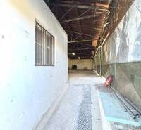 Narrow inner passage in warehouses and halls with metal flooring and pipes.