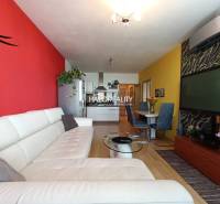 Living room with a white couch, decorative walls, and a dining table in a two-room apartment.