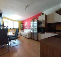Living room with kitchen in a 2-room apartment, with light decor and a dining table.