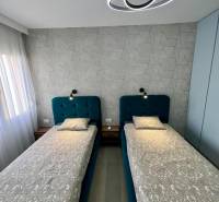Double bedroom with geometric wallpaper and modern lighting in a holiday apartment.