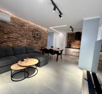 Living room in a holiday apartment with a brick wall, sofa, and television.