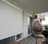 Balcony with wall-mounted blinds, hanging basket, grill, and view, recreational apartment Sarandë.