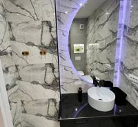 Bathroom in a holiday apartment with a round mirror and elegant tiles.