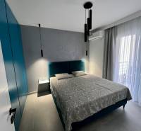 A room with a comfortable bed, a wardrobe, curtains, and balcony doors.