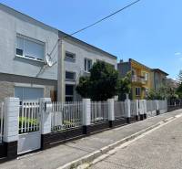 A street with family houses in Komárno, with a white fence and a satellite dish.