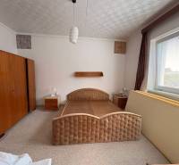 A bedroom in a family house with a large bed and wooden wardrobes.