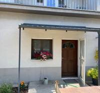 A family house in Komárno with a terrace and flowers in front of the entrance.