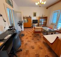 Living room in a family house with older furniture and a table fan.