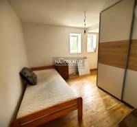 A room with a single bed, a wardrobe, and two windows in a family house.