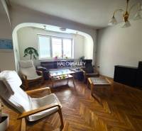 A living room in a family house with armchairs and a brown sofa.