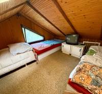 Attic room in a cottage with three beds and a television.
