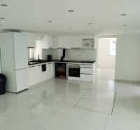 A kitchen in a family house with built-in appliances and glossy tiles.