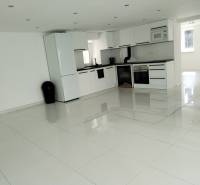 A kitchen in a family house with white furniture and ceramic flooring.