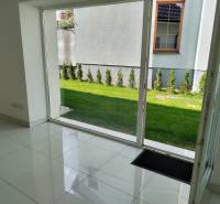 Interior of a family house, white floor, large window with a view of the garden.