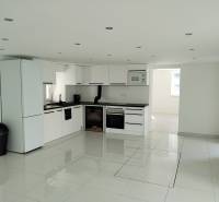 White kitchen with fully equipped appliances and a glossy floor in a family house.