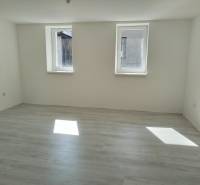 A bright room with two windows and laminate flooring in a family house.
