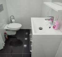 Bathroom in a family house with a toilet, sink, and white tiles.