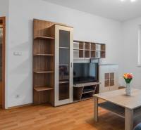 Living room in a two-room apartment with wooden furniture, a television, and a coffee table.