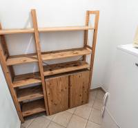 Wooden shelves next to the refrigerator and microwave in a 2-room apartment.
