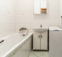 Bathroom with a bathtub, sink, cabinet, and washing machine in a 2-room apartment.