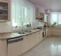 A spacious kitchen in a family house with wooden cabinets and many windows.
