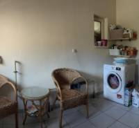 Laundry room in a family house with a washing machine, boiler, and wooden furniture.