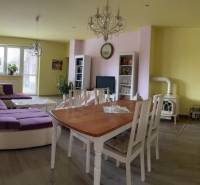 Living room in a family house, light walls, large purple sofa, dining table.
