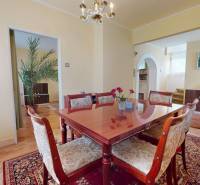 Dining room with a wooden table and chairs in a family house, light walls and a carpet.