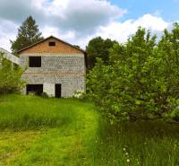 A family house in Čelovce with a garden and trees, surrounded by green nature and the sky.