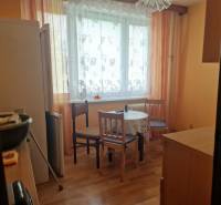 Kitchen in a studio apartment with a table, chairs, and a refrigerator.