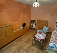 A room with wooden furniture and an armchair in a studio apartment.