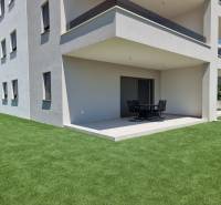 The exterior of a 4-room apartment in Vodice with a modern terrace and green lawn.