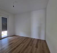 An empty room with wooden flooring and balcony doors in a 4-room apartment.