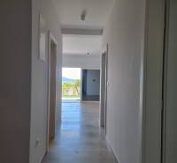 A hallway in a 4-room apartment with a view of the exterior and greenery.